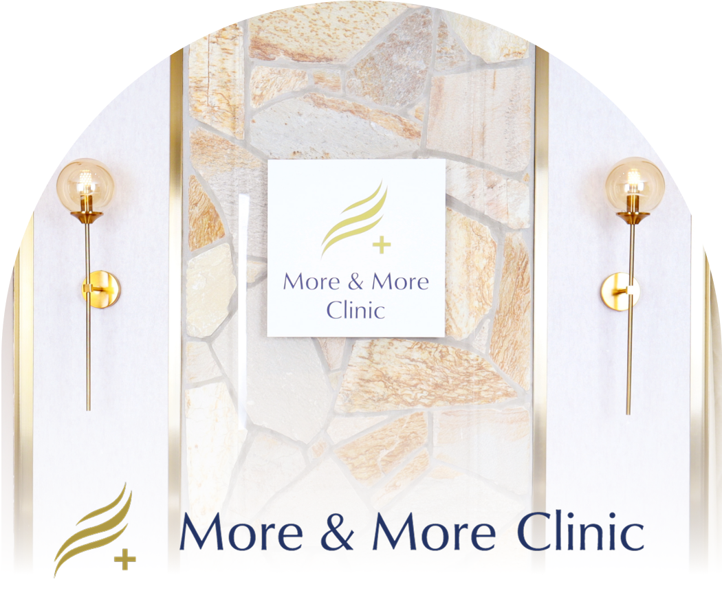 ゴールドの壁灯が左右に設置された、上品でモダンなデザインのクリニック入口の一部。