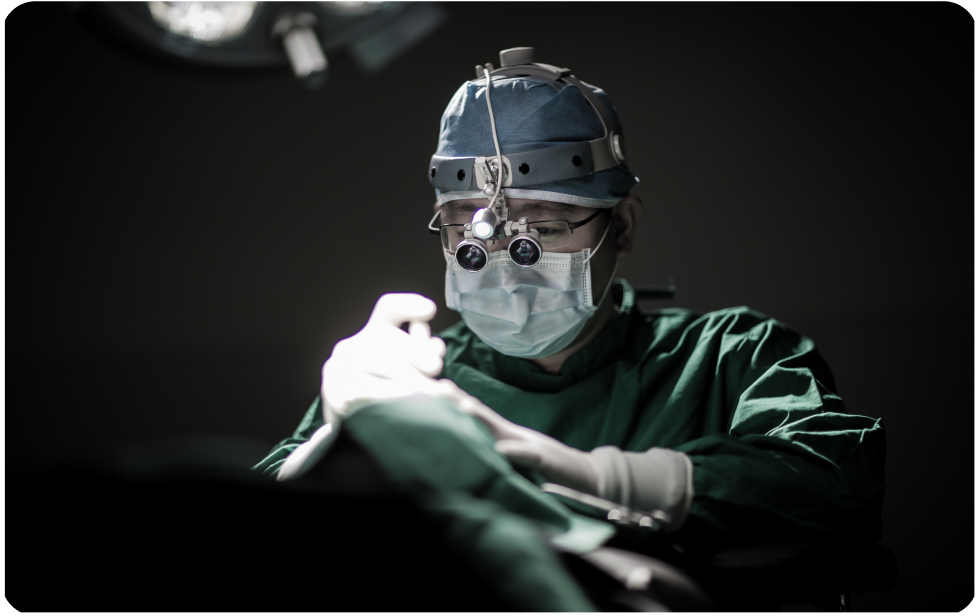 手術ライトの下で治療中の医師